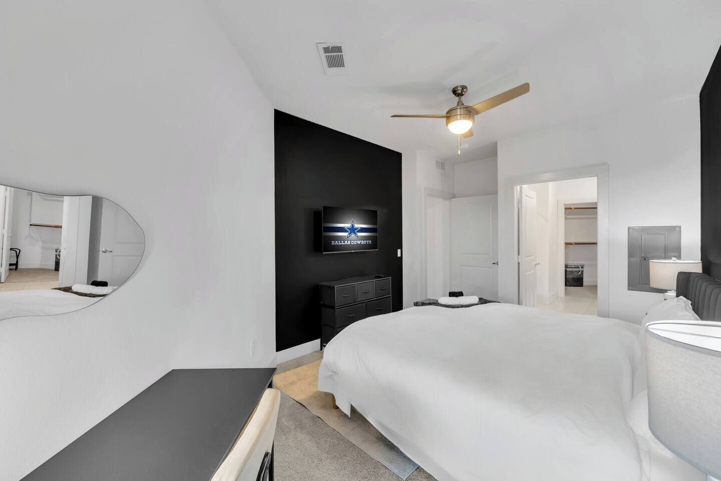 A modern hotel room with a large bed, a flat-screen TV, a ceiling fan, and a walk-in closet.