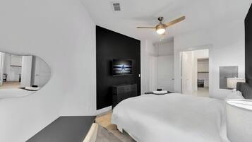 A modern hotel room with a large bed, a flat-screen TV, a ceiling fan, and a walk-in closet.