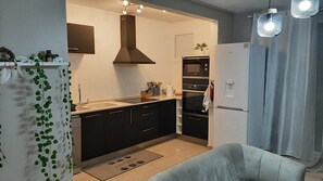 A modern kitchen with black cabinets, a built-in oven, a microwave, and a refrigerator. - O Ti Kolibri - Your Martinican cocoon (Sainte-Luce)