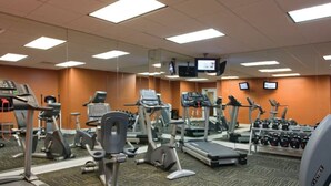 Een fitnessruimte met loopbanden, elliptische trainers en losse gewichten.