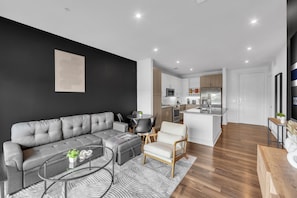 A modern living room with a grey sofa, a round coffee table, and a small white chair. - FriscoSquare+Gym+ToyotaStadium+Pool+PGAGolf+W+D (Frisco)
