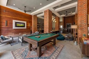 A pool table in a room with a brick wall, a television, and a bar area. - FriscoSquare+Gym+ToyotaStadium+Pool+PGAGolf+W+D (Frisco)