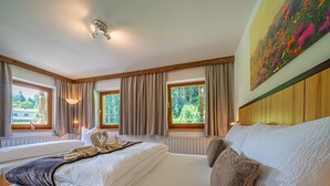Ein Hotelzimmer mit zwei Betten, großen Fenstern und einem Gemälde.