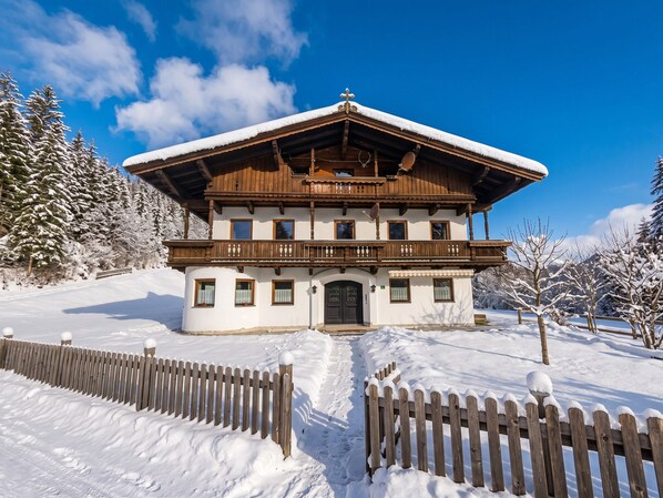 A chalet with a wooden facade, multiple windows, and a snow-covered roof.