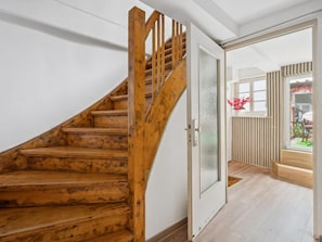 A wooden staircase leading to a room with a glass door, a window with a view of the outdoors, and a wooden floor.