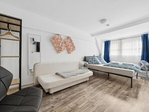 Ein modernes Schlafzimmer mit Sofa, Bett, Schreibtisch und einem an der Wand hängenden Kunstwerk.