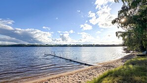 A beach with a wooden pier extending into calm water, surrounded by trees and a distant shoreline. - Amazing home in Kil with lake view (Kil)