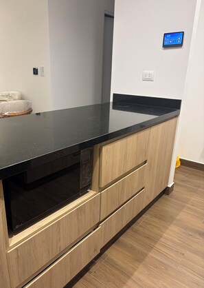 A kitchen with a black countertop, wooden cabinets, and an LG microwave. - New Apartment in Miraflores (Miraflores)