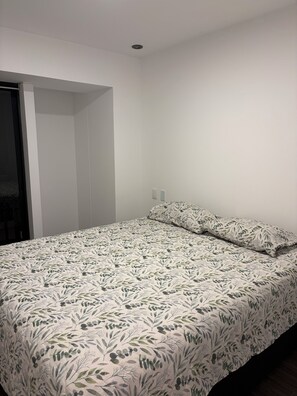 A bedroom with a bed, a door, and a white wall. - New Apartment in Miraflores (Miraflores)