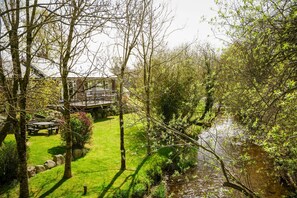Um jardim com mesa para piquenique, um riacho pequeno e uma ponte.
