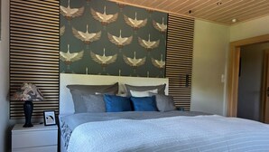A bedroom with a bed, nightstands, a lamp, and a wall with a bird pattern. - Bella's Eden 1 romantic vacation in the countryside directly on the Mulde river (Grimma)