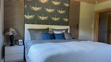 Ein Schlafzimmer mit einem Bett, Nachttischen, einer Lampe und einer Wand mit Vogelmuster.