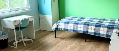 A bedroom with a bed, desk, chair, wardrobe, and a ceiling fan.