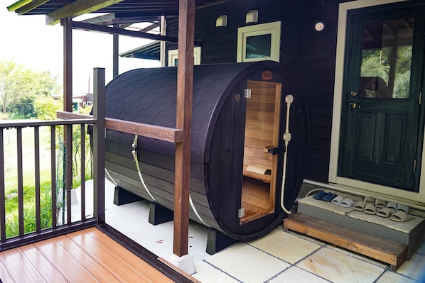 A sauna with a wooden interior, a wooden door, and a bench outside.