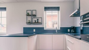 A modern kitchen with white cabinets, a black countertop, a window with a view, and a coffee maker. - Watervilla Wellness 8 (Medemblik)