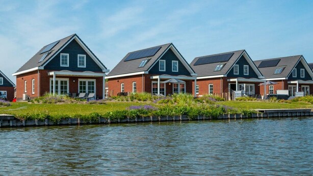 A row of houses with a canal in the foreground. - Watervilla Wellness 8 (Medemblik)