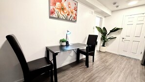 Ein Zimmer mit Schreibtisch, zwei Stühlen, einem Blumentopf und einer Tür.