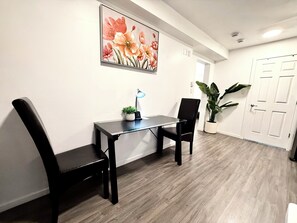 Ein Zimmer mit Schreibtisch, zwei Stühlen, einem Blumentopf und einer Tür.
