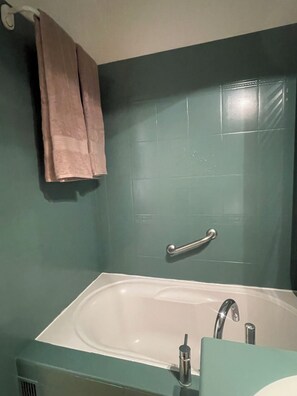 A bathroom with a bathtub, a handrail, and a towel hanging on the wall. - Pool studio with beach access (Sanary-sur-Mer)
