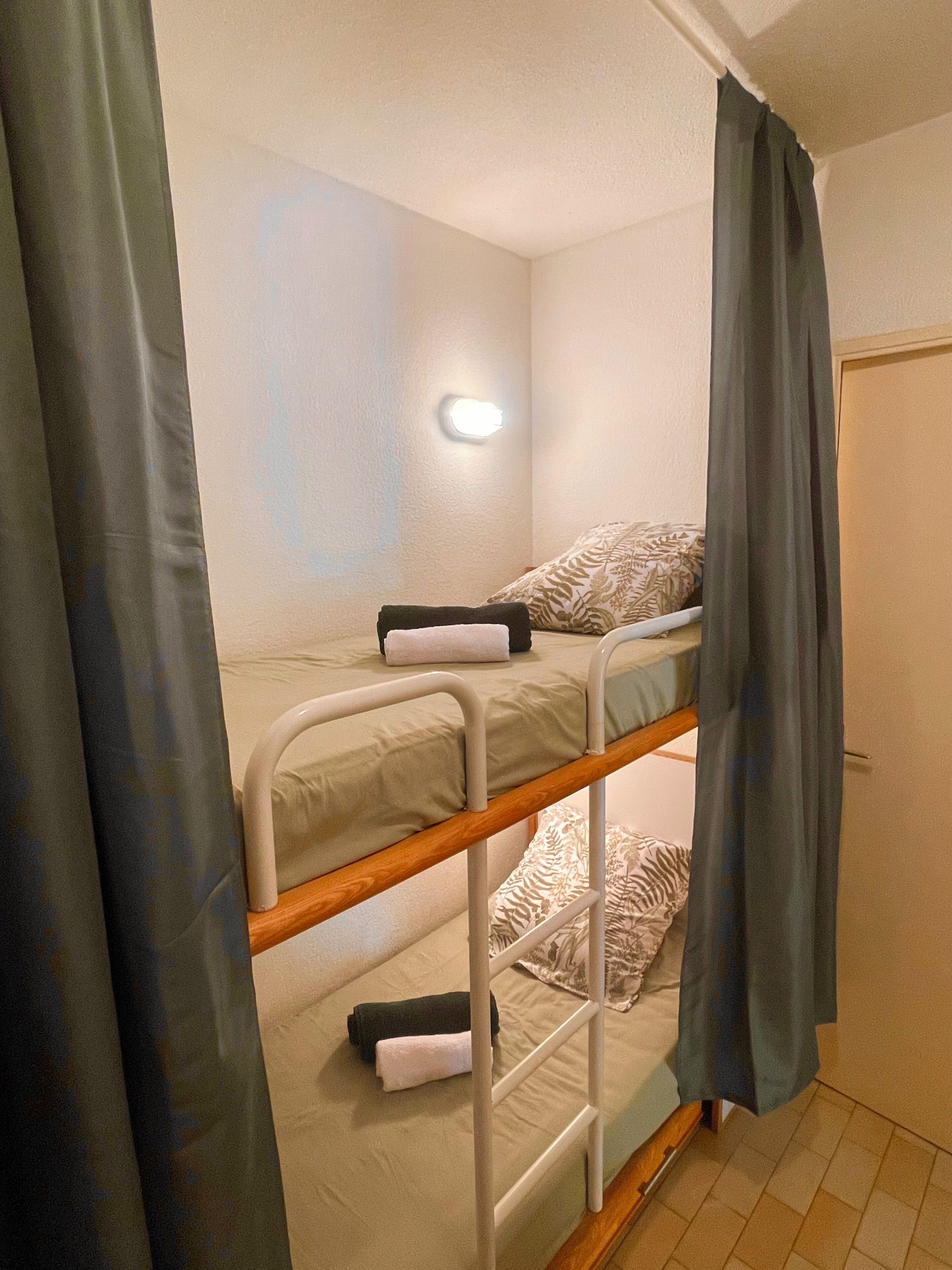 A bunk bed with a headboard, a bedside table, and a wall-mounted light fixture.
