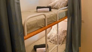 Een stapelbed met hoofdeinde, nachtkastje en een wandlamp.