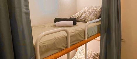 A bunk bed with a headboard, a bedside table, and a wall-mounted light fixture.
