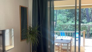 Een kamer met een televisie, een plant, een tafel en uitzicht op een terras.