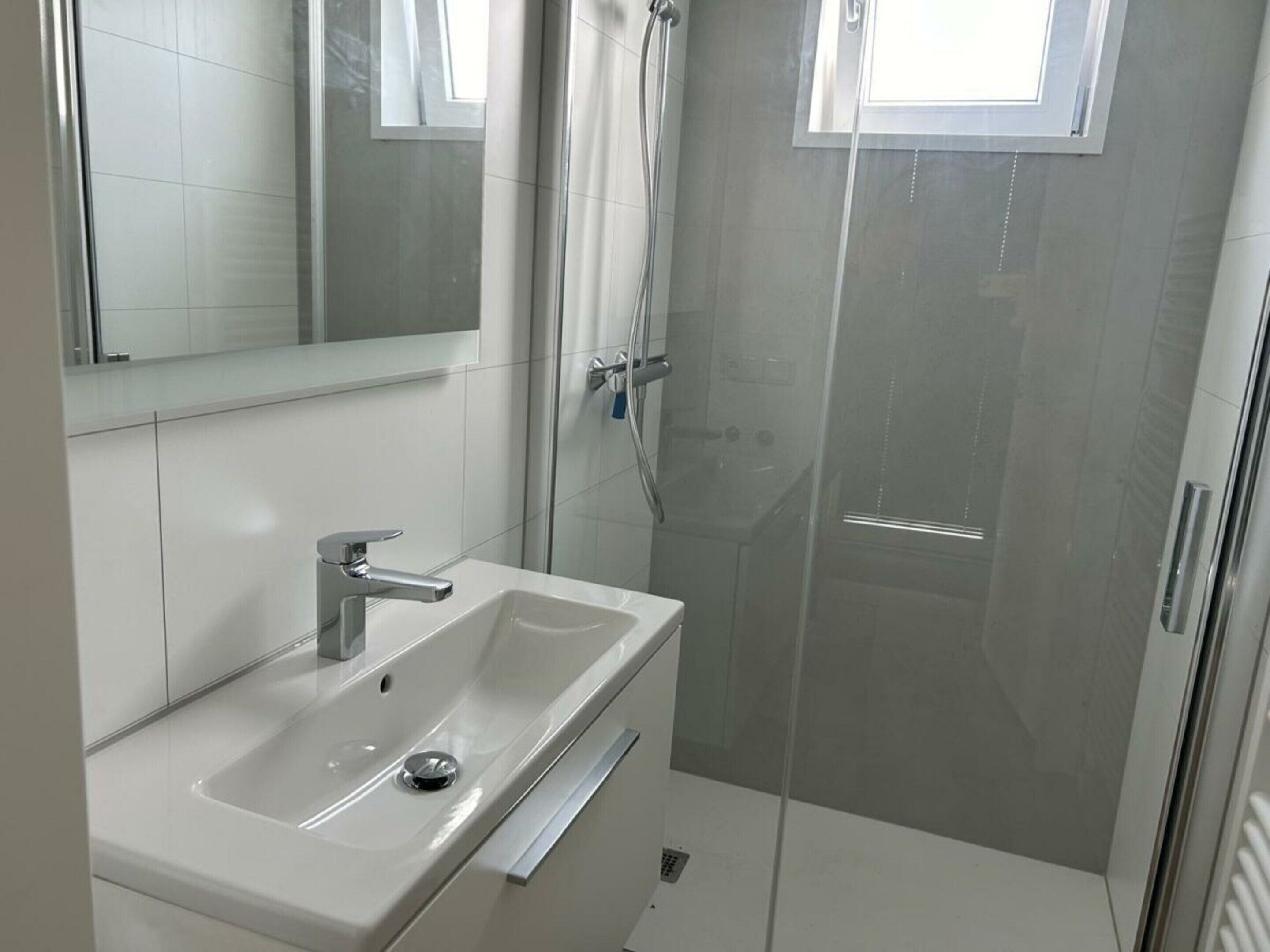 Ein Badezimmer mit Waschbecken, Spiegel und Duschkabine.