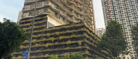 A tall, uniquely designed building with multiple balconies and greenery.