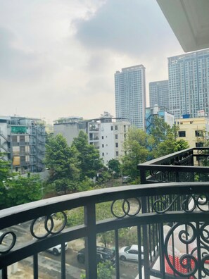 Ein Balkon mit Metallgeländer, der auf eine Stadtansicht mit verschiedenen Gebäuden und einer Straße blickt.