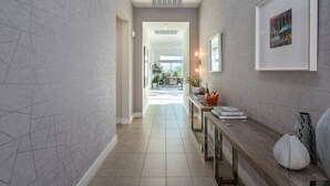 Un pasillo con diseño moderno, que incluye un mueble consola con objetos decorativos y un cuadro en la pared.
