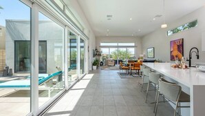 Una cocina moderna con barra, ventanas amplias y zona de comedor.