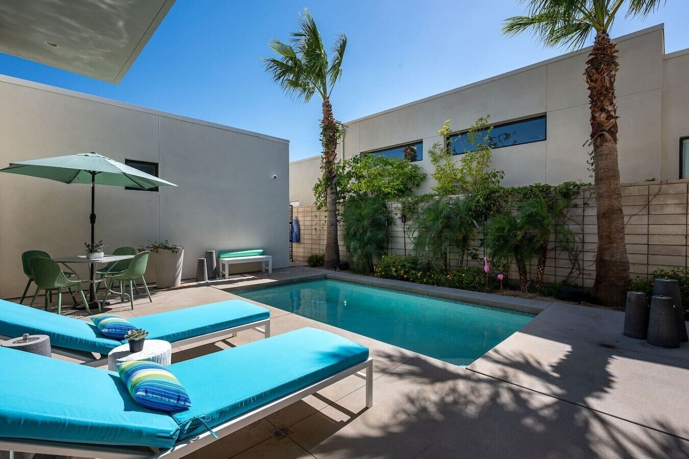A modern outdoor pool area with lounge chairs, a table, and a bench.