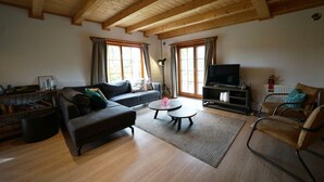 Una sala de estar con sofá, mesa de centro, televisor y una silla.