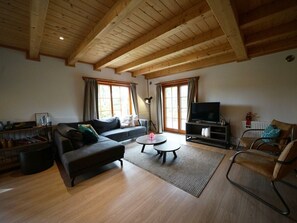 Ein Wohnzimmer mit einer Couch, einem Couchtisch, einem Fernseher und einem Sessel.