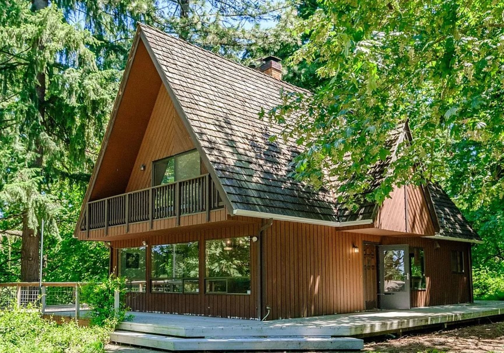 A cabin with a sloped roof, a balcony, and a covered porch area.