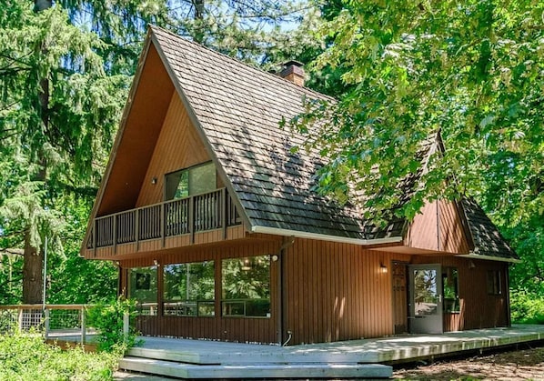 A cabin with a sloped roof, a balcony, and a covered porch area.