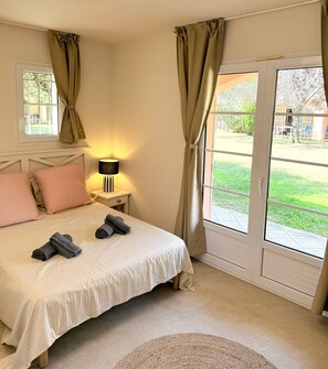 A bedroom with a bed, pillows, a lamp, a window, and a view of the outdoors. - Air-conditioned apartment with a heated pool, 10 minutes from Saint-Tropez (Grimaud)