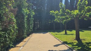 Ein Hof mit Kiesweg, umgeben von Bäumen und Gras.