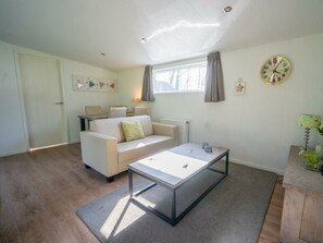 A modern living room with a sofa, coffee table, and a clock on the wall. - Holiday Home in Lochem With Terrace (Lochem)