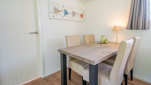 A dining area with a wooden table, six chairs, a lamp, and a painting on the wall.