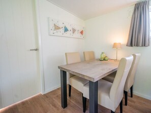 A dining area with a wooden table, six chairs, a lamp, and a painting on the wall. - Holiday Home in Lochem With Terrace (Lochem)