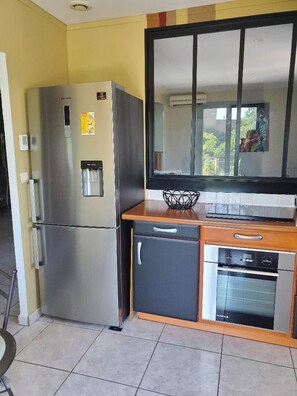 Eine kleine Küche mit Kühlschrank, Backofen und Mikrowelle.