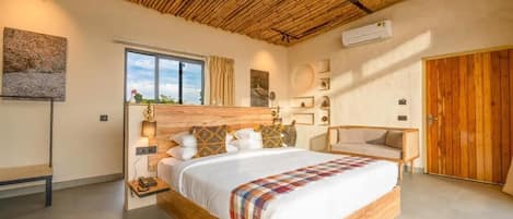 A bedroom with a large bed, a wooden headboard, a window with curtains, and a wooden wardrobe.