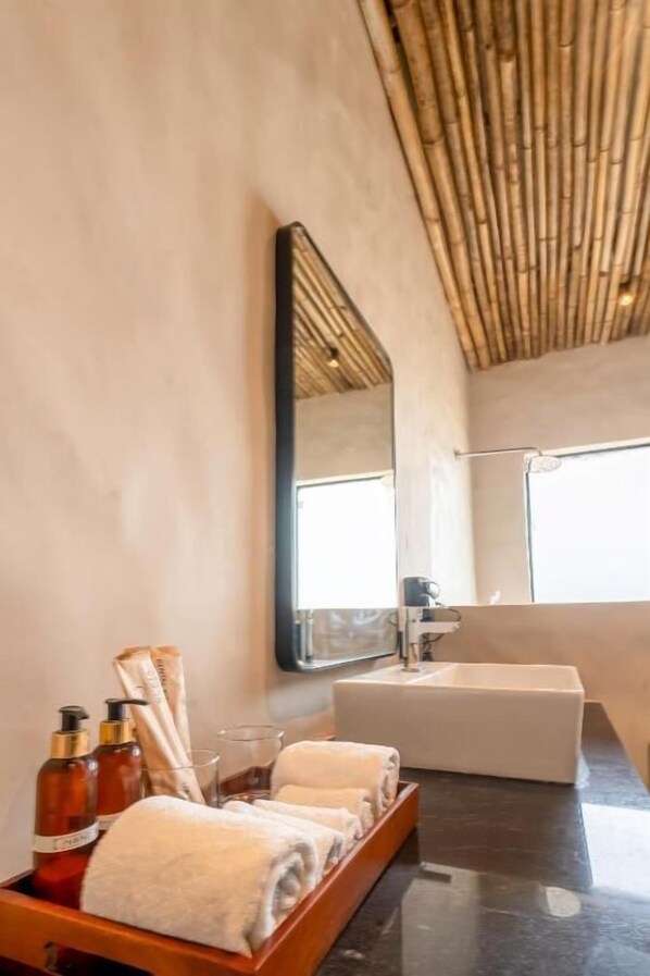 A modern bathroom with a large mirror, a bathtub, and a wooden tray with towels and toiletries.
