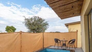 Una piscina con techo de madera y una mesa con sillas.