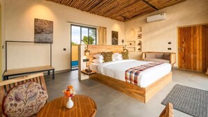 Un dormitorio moderno con una cama grande, mesitas de noche, un banco de madera y una mesa redonda con flores.