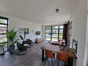 Ein modernes Wohnzimmer mit Essbereich, großen Fenstern und Blick ins Freie.