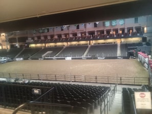 An indoor arena with multiple levels of seating, a dirt track, and a 'STOP' sign.