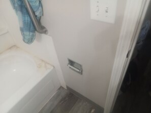 A bathroom with a bathtub, a towel rack, and a toilet paper holder.